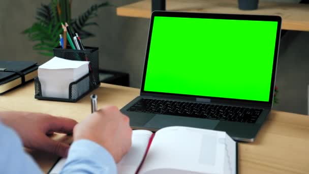Man Student Studie schreibt Informationen in Notizbuch. Laptop mit grünem Bildschirm - Filmmaterial, Video