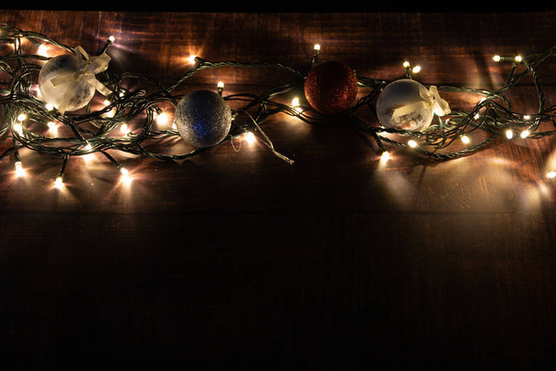 christmas balls with lights on a wooden base. christmas decoration. low key photography - Photo, Image