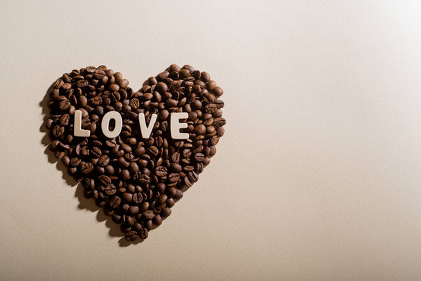 Coffee beans in the shape of a heart and the inscription love on a background - Фото, зображення