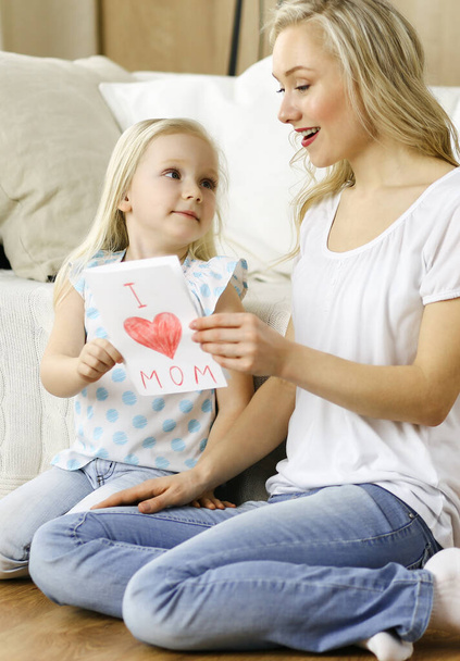 Happy mother day. Child daughter congratulates mom and gives her postcard with heart drawing. Family and childhood concepts - Foto, imagen
