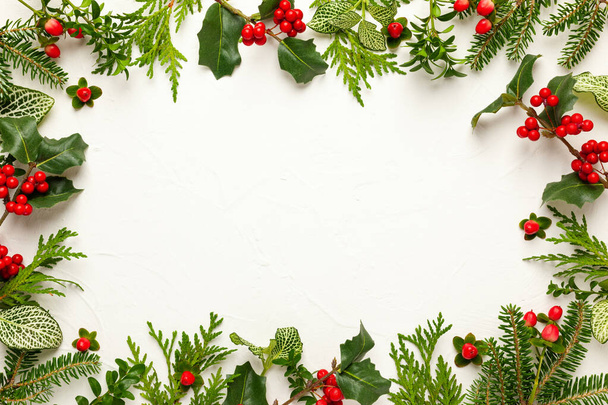 Christmas background with branches of fir tree, evergreens and holly with red berries on white. Winter nature concept. Flat lay, copy space. - Foto, Imagem