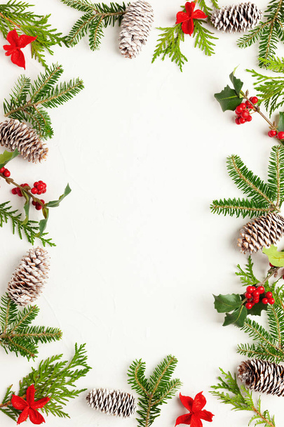 Christmas background with pine cones, branches of holly with red berries and fir tree on white. Winter festive nature concept. Flat lay, copy space. - Photo, image