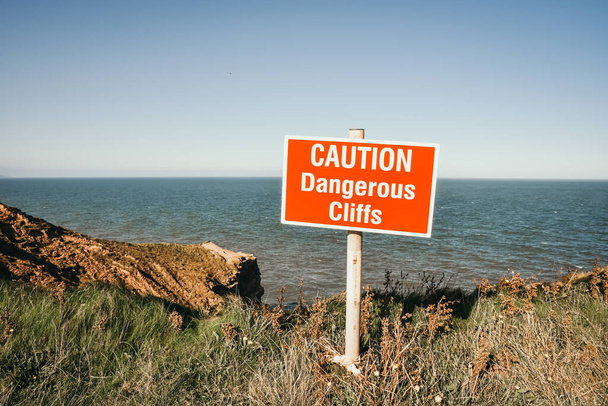 Опасный край скалы знак в пасмурную погоду на скалах Финли в Великобритании - Фото, изображение
