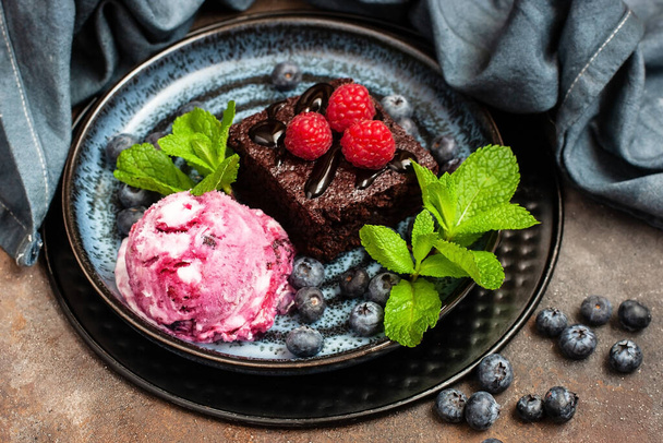 Chocolate brownie with berry, mint leaves and  ice cream ball on dessert tabl - Photo, Image