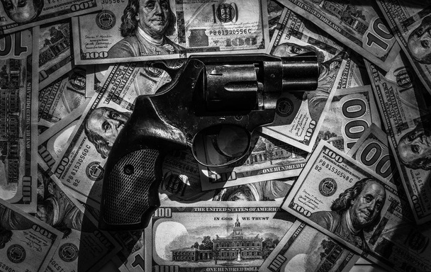 Револьвер лежит на стодолларовых купюрах. - Фото, изображение