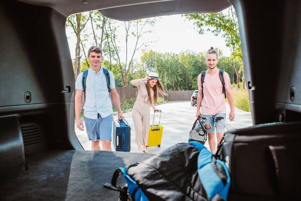 Vrienden laden kofferbak met bagage. zomervakantie. - Foto, afbeelding