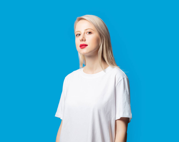 Blonde in white t-shirt on blue background  - Zdjęcie, obraz