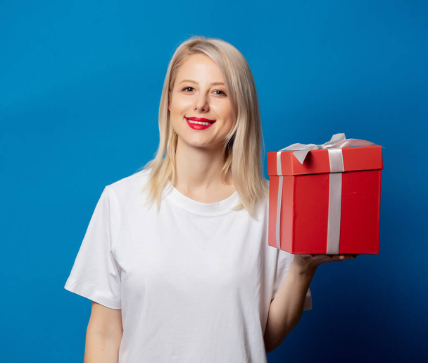 girl in white t-shirt with present box on blue background - Photo, Image