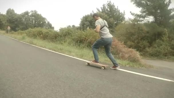 Kleiner Junge in blauer Jeans und grauem T-Shirt beim Schlittschuhlaufen mit dem Skateboard auf einer Straße an einem bewölkten Tag - Filmmaterial, Video