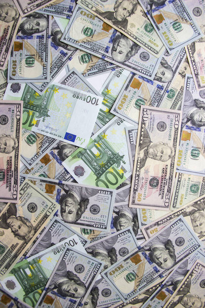 Geld ligt in een hoop op de tafel verspreid. Dollars en eurogeld liggen chaotisch op tafel.  - Foto, afbeelding