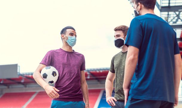 Les joueurs de football dans le stade de football pendant covid-19 portant des masques - Photo, image