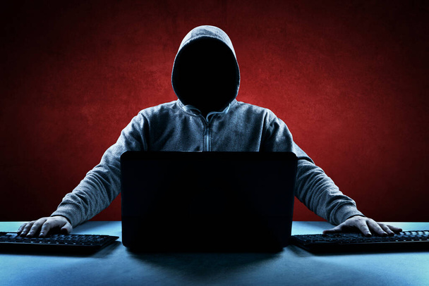 A hacker kiírja a kódot egy laptop billentyűzetén, hogy betörjön egy kibertérbe. - Fotó, kép