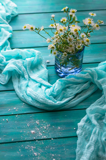 Blooming chamomile flowers on a teal blue wooden background, vertical image - Photo, Image