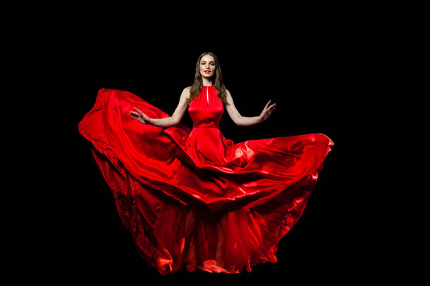 Όμορφη διασημότητα νεαρή γυναίκα σε κόκκινο μεταξένιο φόρεμα σε μαύρο φόντο - Φωτογραφία, εικόνα