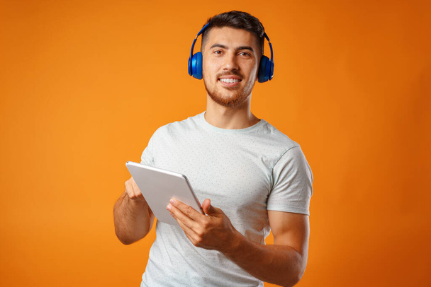 Handsome young mixed-race man listening to music with blue headphones - Foto, imagen