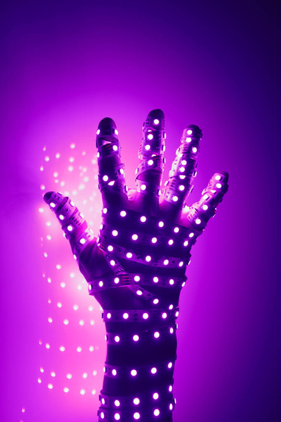 menselijke hand bedekt met paarse led-verlichting, verlichte achtergrond - Foto, afbeelding