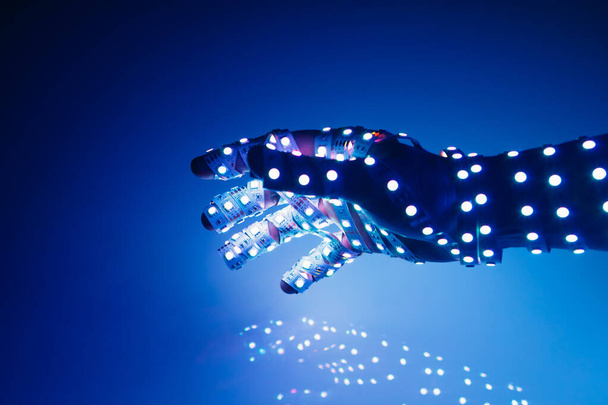 menselijke hand bedekt met blauwe led-verlichting, verlichte achtergrond - Foto, afbeelding