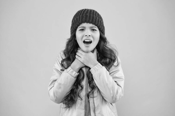 she has sore throat. cold climate weather. happy little girl pink background. kid puffer jacket and knitted hat. winter shopping. how to dress warm in winter. ready for cold winter. no flu - Foto, Imagen