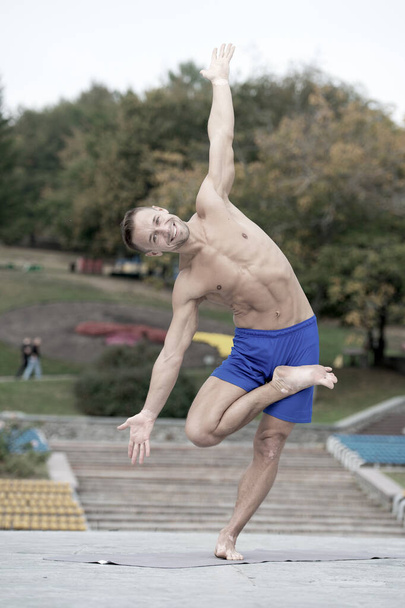 Athletic man doing yoga asanas in the park - Valokuva, kuva
