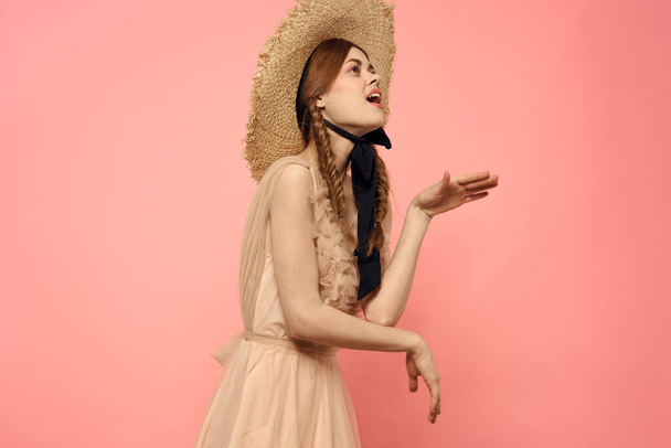 Modna kobieta w sukience i kapeluszu z czarną wstążką na różowym tle przycięty widok emocji modelu zabawy - Zdjęcie, obraz