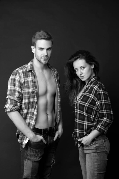 Family look. Fashion trend. Fashionable outfit. Woman and man wear checkered shirt. Sexy stylish couple black background. Young family couple. Summer fashion collection. Beautiful people concept - Zdjęcie, obraz