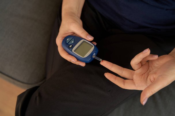 Close up of middle aged woman hands with glucose meter. Blood testing at home. Metabolic syndrome - Foto, Imagem