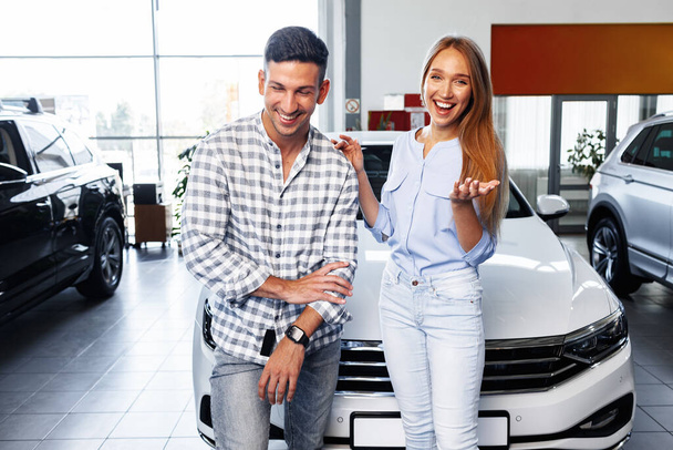 Cherrful young couple at the dealership buying a new car - Photo, image