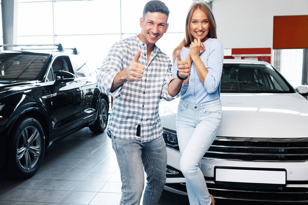 Cherrful young couple at the dealership buying a new car - Foto, imagen