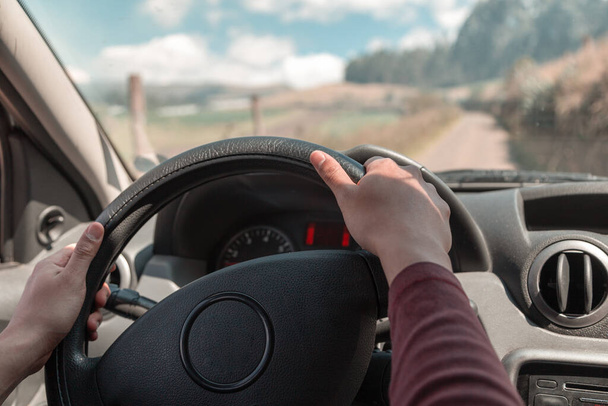 steering wheel of a car while a person is driving, behind the windshield is a countryside landscape - 写真・画像