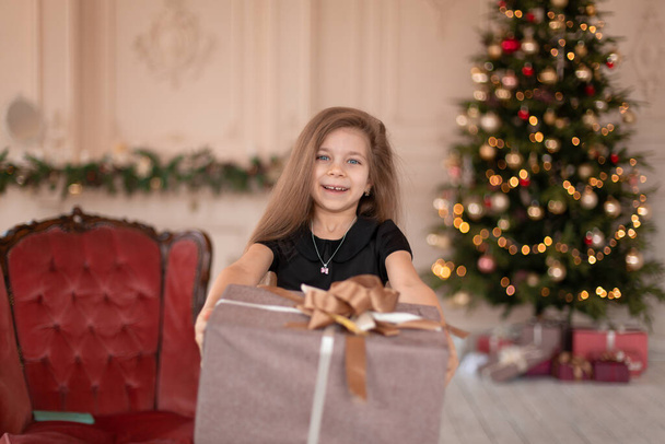 A little girl opens a Christmas present from Santa. Christmas tale. Happy childhood. - Photo, Image