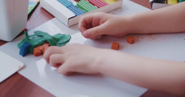 Um menino brinca com argila brilhante ou plasticina, sentado à mesa. - Filmagem, Vídeo