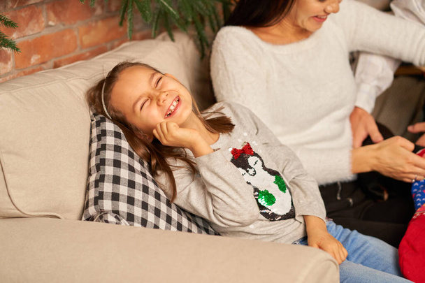 Little girl laughs having fun while spending time with parents at home on the couch. - Fotó, kép