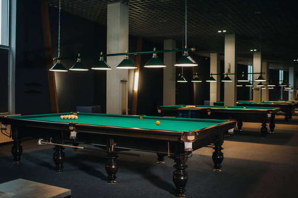 there are a lot of billiard tables with green surfaces and balls in the billiard club. - Foto, Bild
