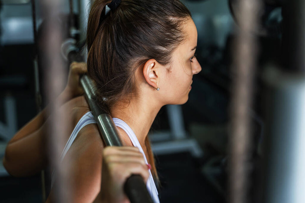Jeune femme caucasienne formation à la salle de gym avec haltères poids faire squats - Photo, image