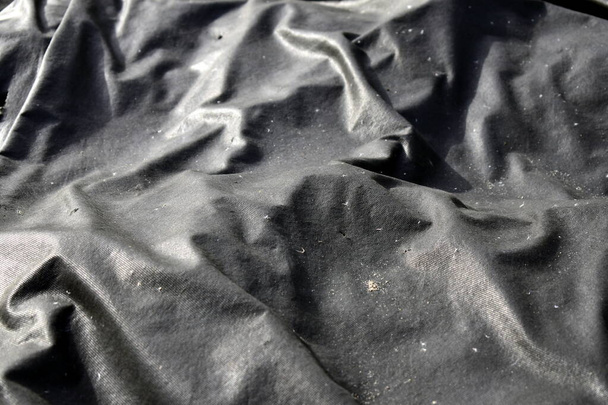 faltiges schwarzes Tuch in der Sonne - Foto, Bild