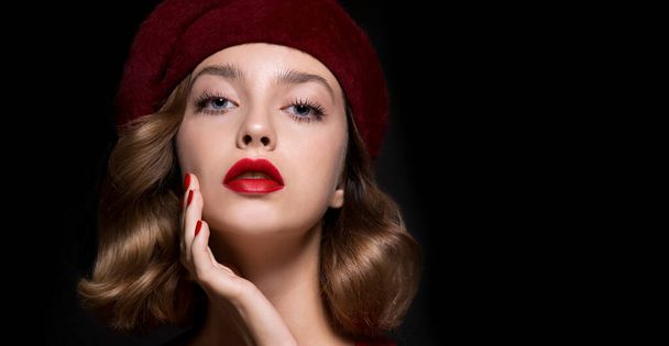 Portrait of beautiful young woman wearing red clothes and beret with perfect young skin, red matt lips and nails.  Model with bright scarlet color makeup and manicure posing on dark background. - Foto, Imagem