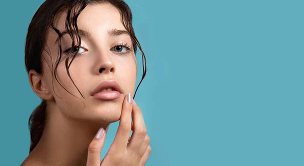 Beautiful young woman with clean perfect skin and water moisture drops touching face. Portrait of beauty model with natural nude makeup moisturizing her skin by lotion. Spa, skincare and wellness. Close up, background, copy space. - Foto, Imagem