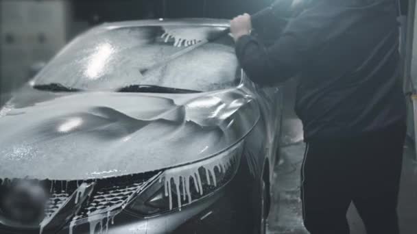 L'uomo lava la sua auto all'autolavaggio self-service, copre l'auto con schiuma di lavaggio - Filmati, video