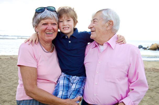 Happy cute kid hugging grandparents in vacation - Photo, Image