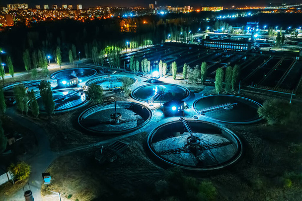 Vista aérea nocturna de la moderna planta de tratamiento de aguas residuales con piscinas redondas para la limpieza de aguas residuales, tiro con drones - Foto, Imagen