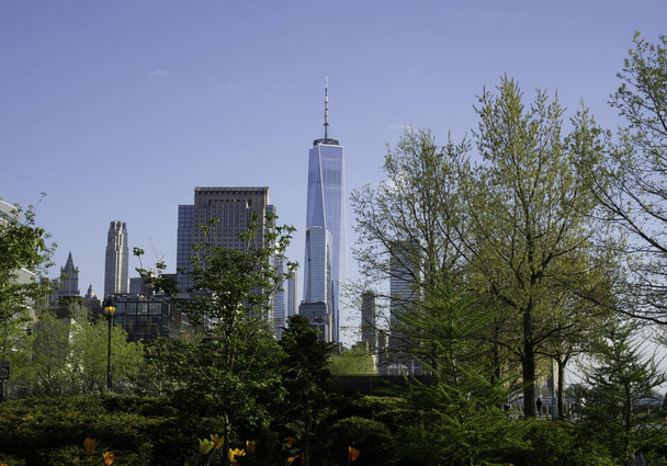 Вид на финансовый район в Лоуэр-Манхэттене, на заднем плане которого находится здание Всемирного торгового центра, открывается с тротуара реки Гудзон - Фото, изображение