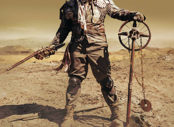 Фото пост-апокаліптичного воїна-рейдера у шкіряній куртці з металевою бронею та рушничною зброєю, що стоїть у пустелі зі знаком черепа
. - Фото, зображення