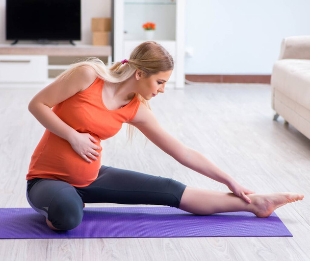 Έγκυος γυναίκα που κάνει γυμναστική στο σπίτι - Φωτογραφία, εικόνα