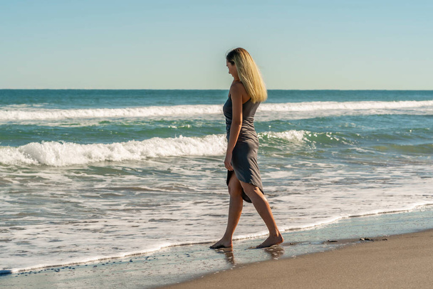 Прекрасная молодая блондинка наслаждается днем на пляже в одиночестве
 - Фото, изображение