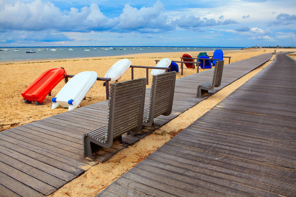 Bateaux touristiques sur la plage de sable fin. Chemin pédestre et banc au bord de la mer - Photo, image