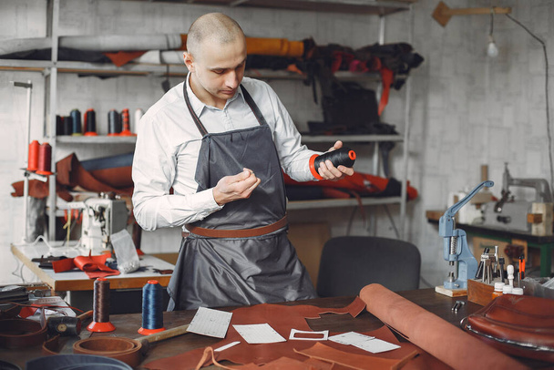 Man in a studio creates leather ware - Zdjęcie, obraz