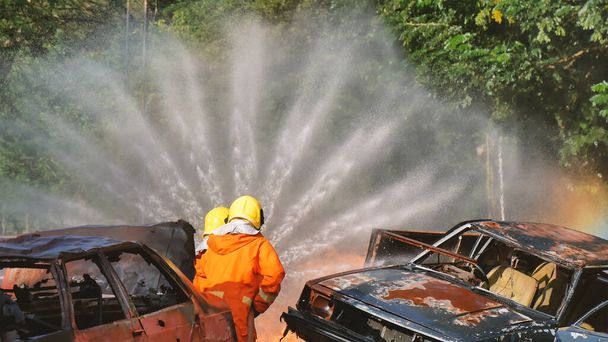 Tűzoltó harcol lánggal tűzoltó tömlő vegyi víz hab spray motor. Tűzoltó viseljen keménykalapot, testvédő egyenruhát a védelemért. Tűzoltó készülékek mentési kiképzése - Fotó, kép