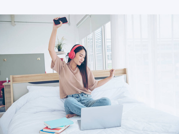 Розслабитися жінка тримає книгу читати на ліжку, використовуючи навушники слухати музику. Молода жінка розслабляється читаючи відкриту книгу розваги розум. Щастя красива жінка людина
 - Фото, зображення