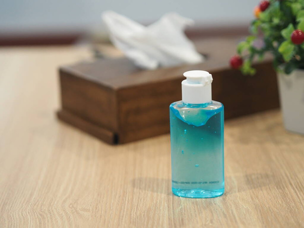 Hand Sanitizer, gel alcoholic mixture with gelatin in clear Plastic bottle with pump pushing wash clean dirty to prevent germs protect Contagious disease coronavirus covid-19, on wooden desk blurred of pop-up Tissue box and mini tree pot - Foto, Imagem
