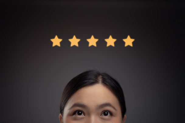 Close up shot of happy Asian woman with five stars icon hologram effect. - Photo, Image